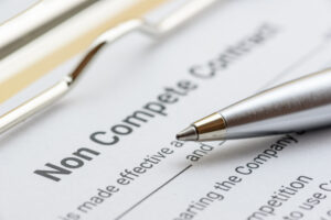 non compete agreement on a clipboard with a silver pen on top