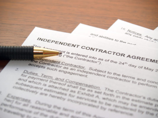 pen resting on a copy of an independent contractor agreement