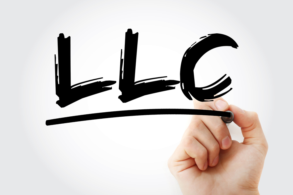 hand writing "LLC" with a black marker