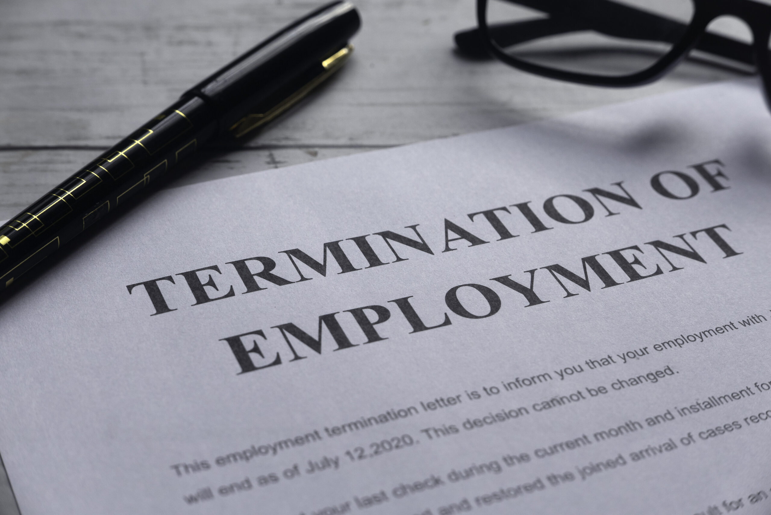 paper with termination of employment written at top with a pen laying on the desk