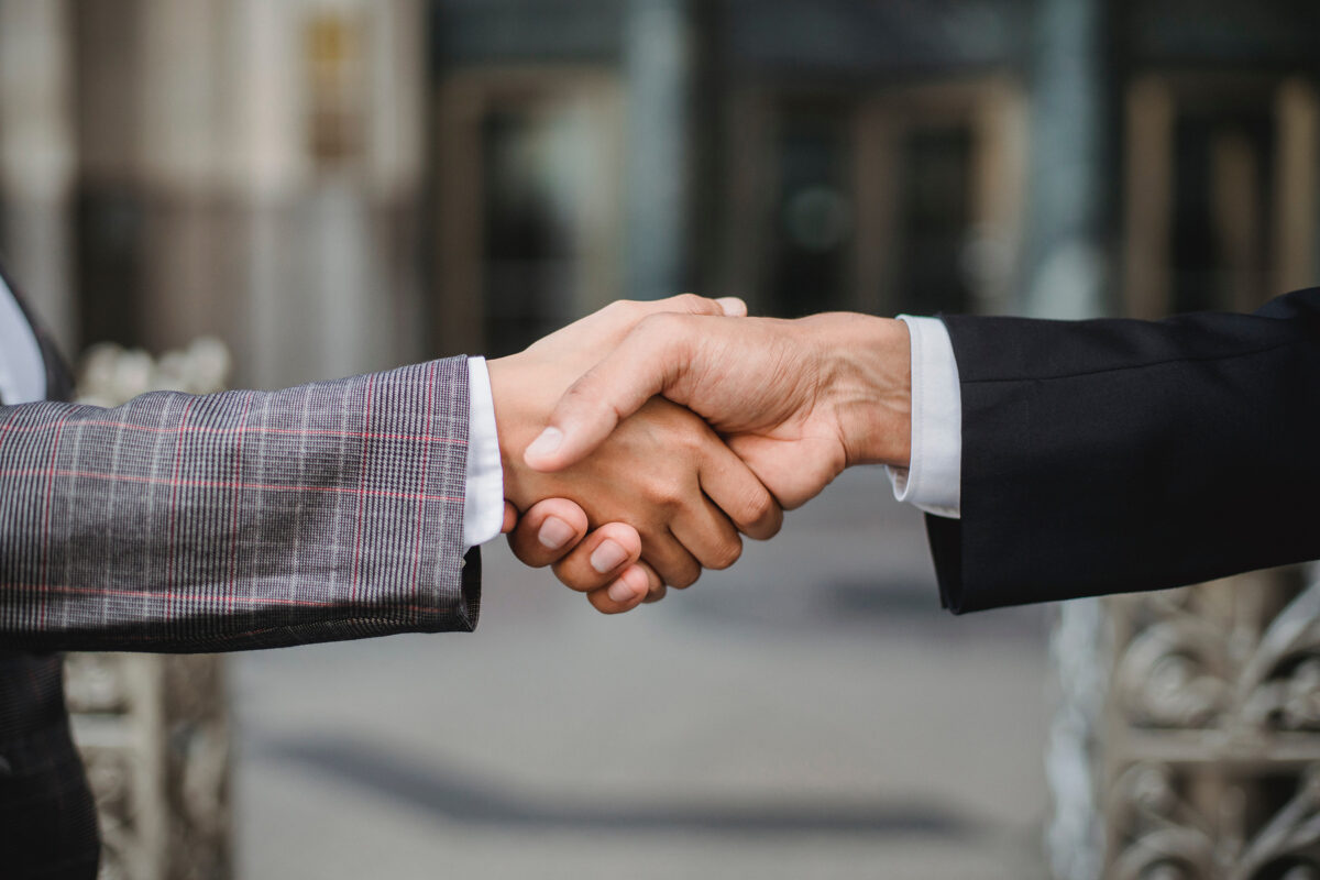 2 people wearing business attire shaking hands